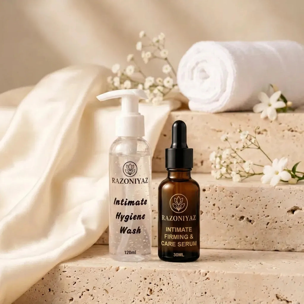 stone steps aur towel wali: Razo Niyaz intimate wash 120ml and serum 30ml on stone steps with ivory satin, a rolled towel and white flowers.